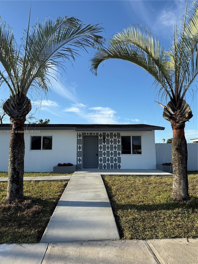 ranch-style home featuring stucco siding and fence