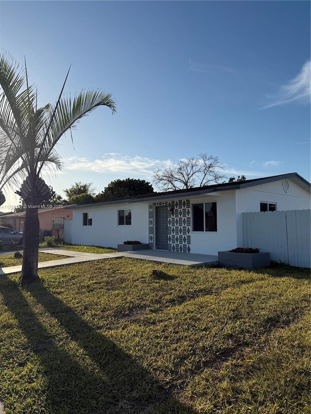 rear view of house featuring a lawn and fence