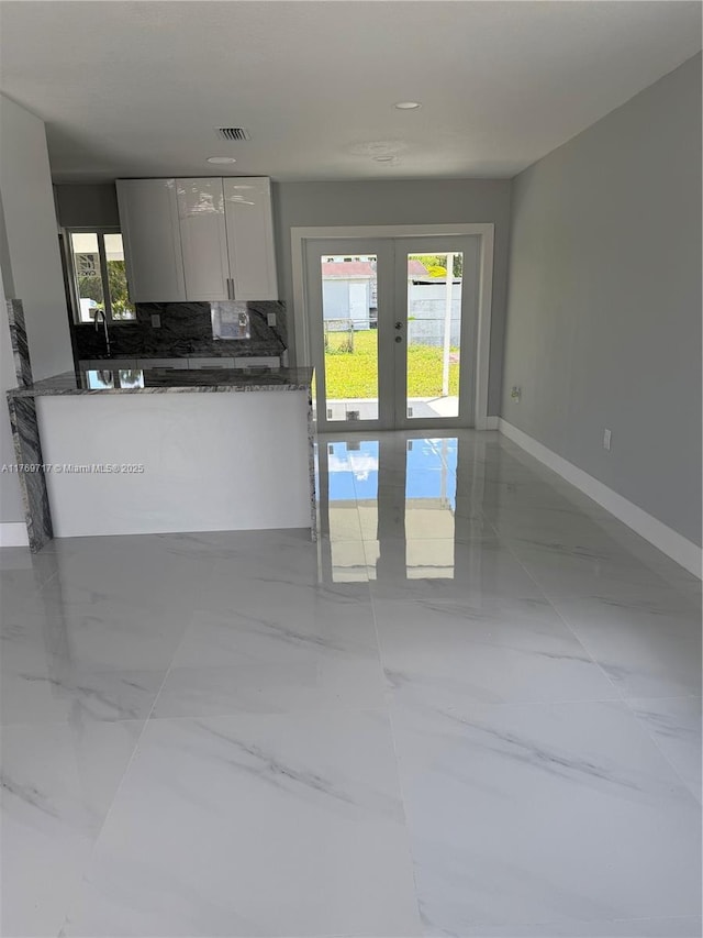 kitchen with a healthy amount of sunlight, white cabinets, visible vents, and french doors
