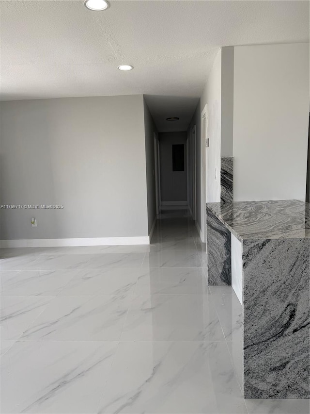 hallway featuring marble finish floor, baseboards, recessed lighting, and a textured ceiling