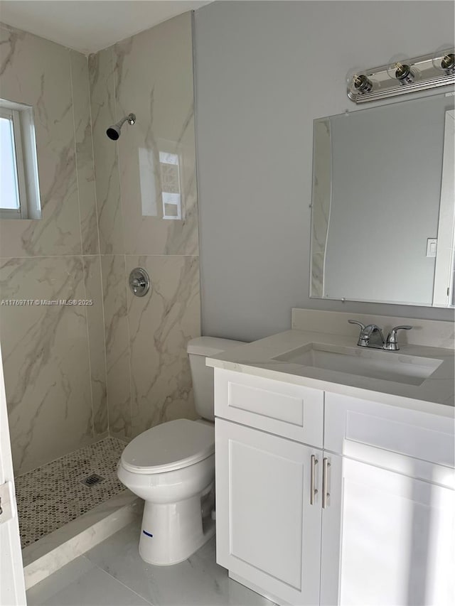 bathroom featuring a marble finish shower, toilet, and vanity