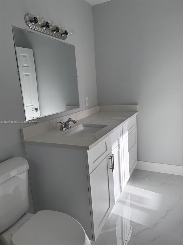 bathroom with toilet, vanity, and baseboards