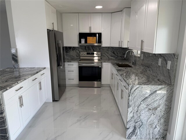 kitchen with light stone counters, a sink, stainless steel appliances, marble finish floor, and white cabinets