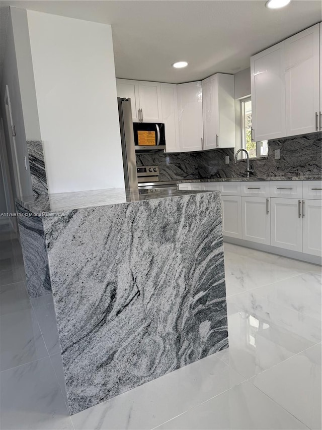 kitchen with white cabinetry, tasteful backsplash, stone counters, and stainless steel appliances