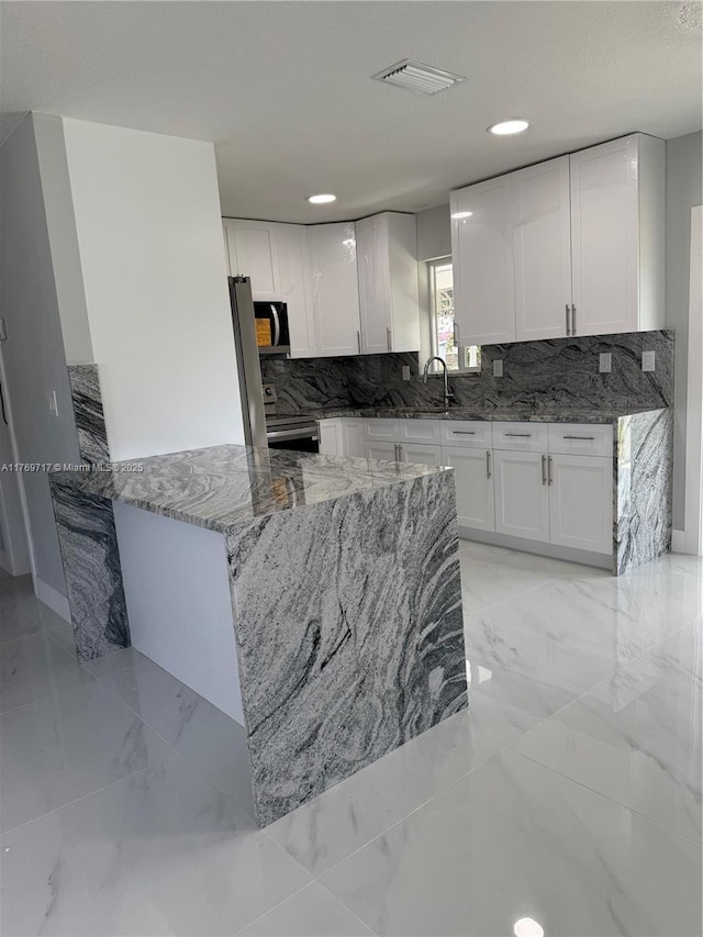 kitchen featuring marble finish floor, white cabinetry, light stone counters, and visible vents