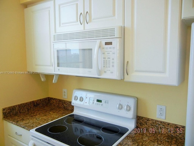 interior details with dark countertops, white cabinetry, and white appliances