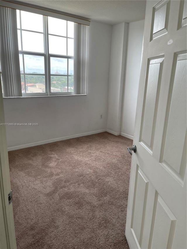 unfurnished room featuring carpet flooring and baseboards