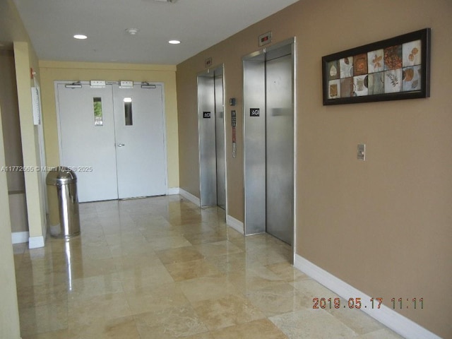 corridor with elevator, recessed lighting, and baseboards