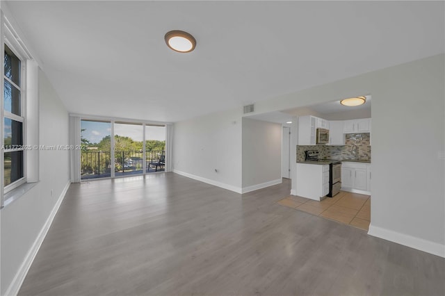 unfurnished living room with visible vents, a sink, light wood finished floors, and baseboards