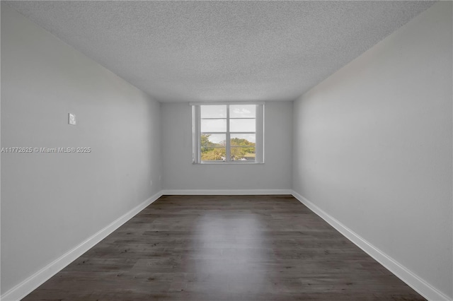 unfurnished room with baseboards, dark wood finished floors, and a textured ceiling