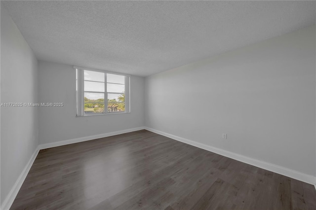 spare room with dark wood-type flooring, a textured ceiling, and baseboards