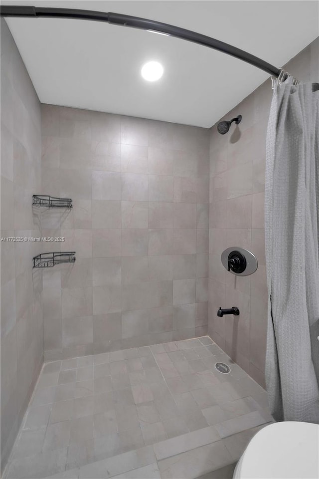 bathroom with toilet and tiled shower