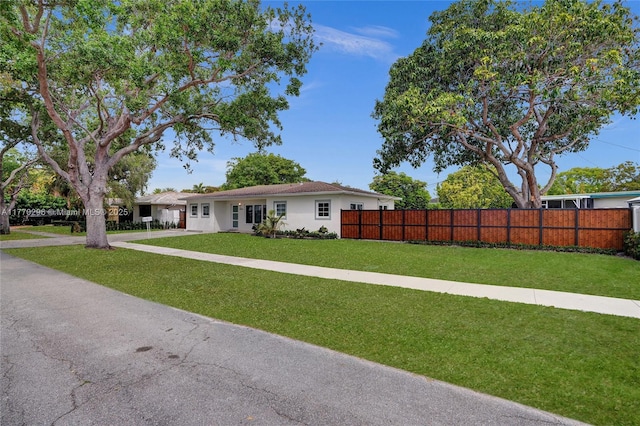 ranch-style home with stucco siding, a front yard, and a fenced front yard