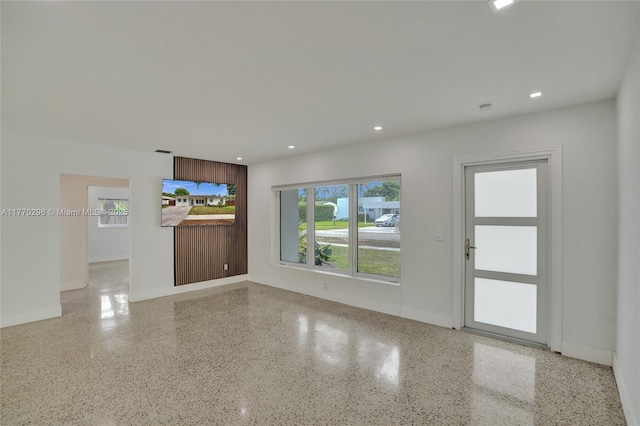 unfurnished living room with visible vents, speckled floor, and recessed lighting