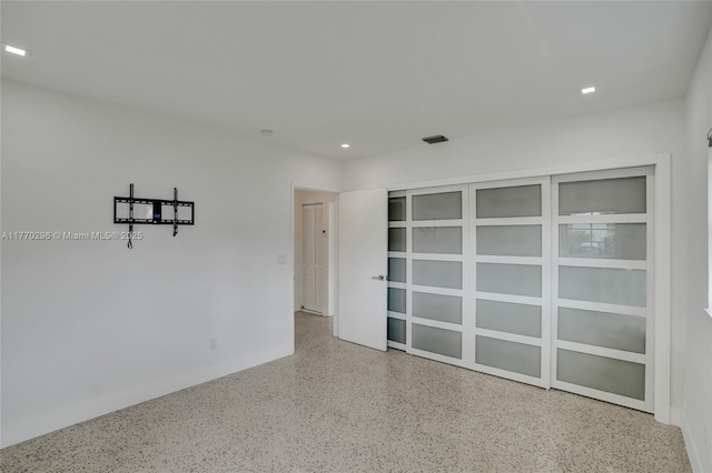 empty room with visible vents, speckled floor, and recessed lighting