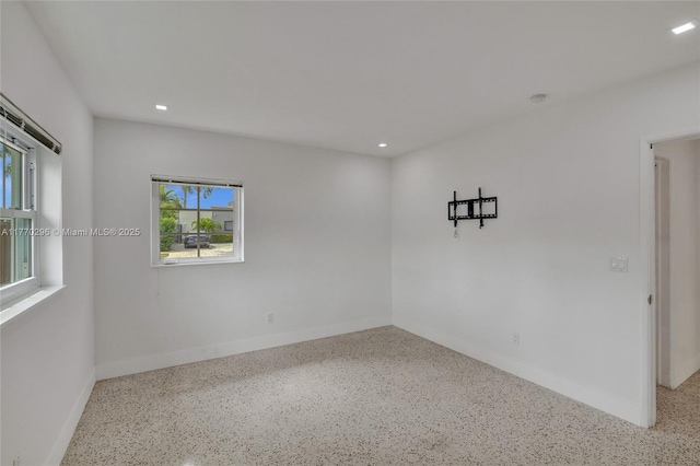 unfurnished room featuring speckled floor, baseboards, and recessed lighting