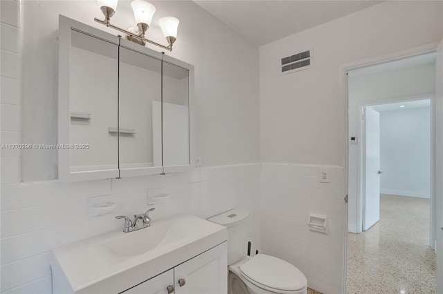 bathroom with vanity, tile walls, toilet, speckled floor, and visible vents