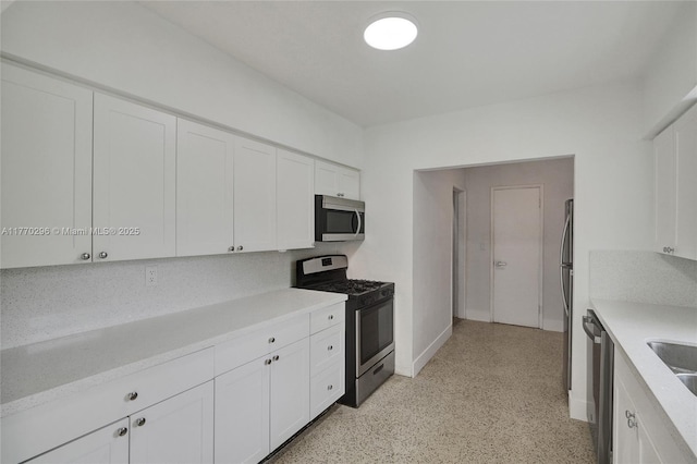 kitchen featuring light speckled floor, white cabinetry, light countertops, and appliances with stainless steel finishes