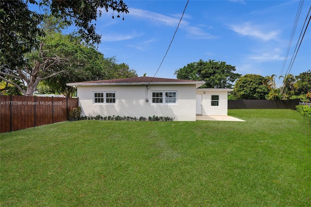 rear view of house featuring a fenced backyard, stucco siding, a patio, and a yard