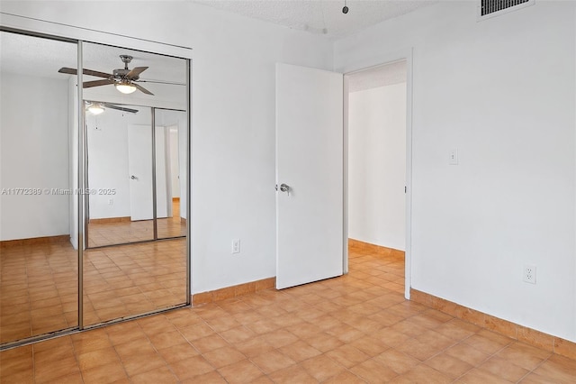 unfurnished bedroom featuring visible vents, baseboards, a closet, a ceiling fan, and a textured ceiling