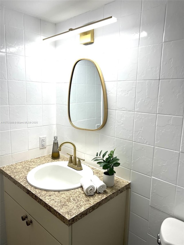 bathroom featuring toilet, tasteful backsplash, vanity, and tile walls