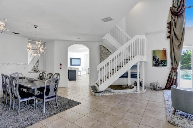 721 Ranch Rd, Weston, FL 33326 - tiled dining room with stairs, arched walkways, a chandelier, and a high ceiling