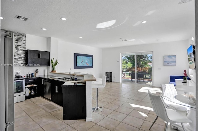 721 Ranch Rd, Weston, FL 33326 - kitchen featuring a kitchen bar, open floor plan, dark cabinets, a peninsula, and decorative backsplash