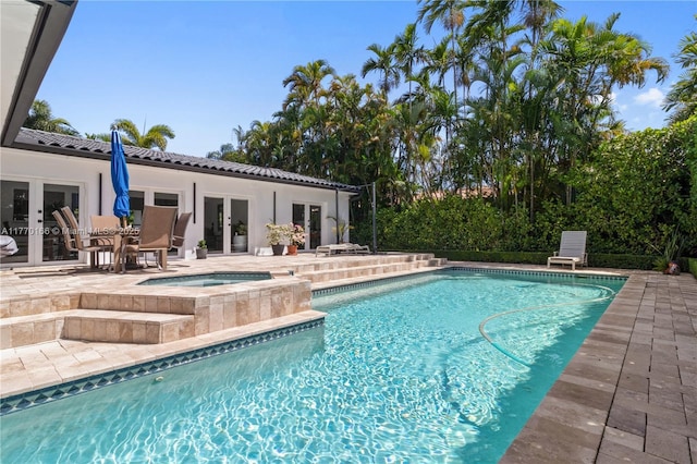 outdoor pool featuring french doors, an in ground hot tub, and a patio