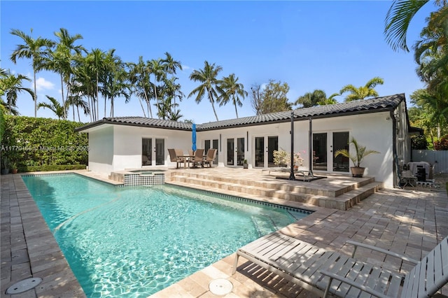 view of swimming pool featuring a patio area, french doors, and a pool with connected hot tub