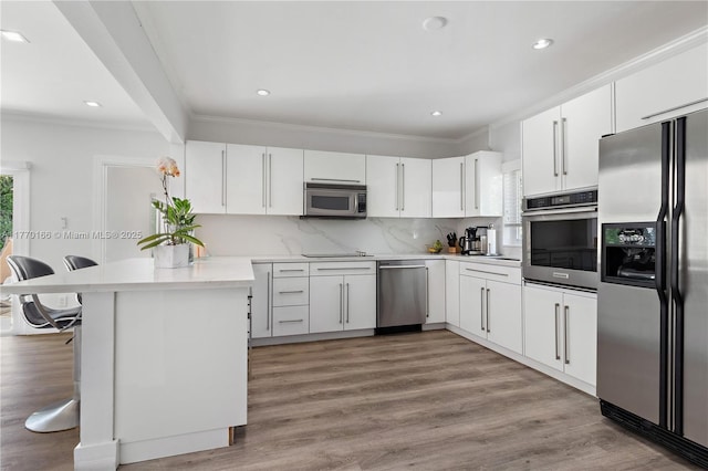 kitchen featuring tasteful backsplash, a peninsula, light wood-style flooring, light countertops, and appliances with stainless steel finishes