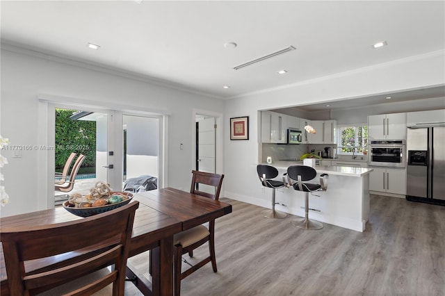 dining space with light wood-style floors, recessed lighting, visible vents, and ornamental molding