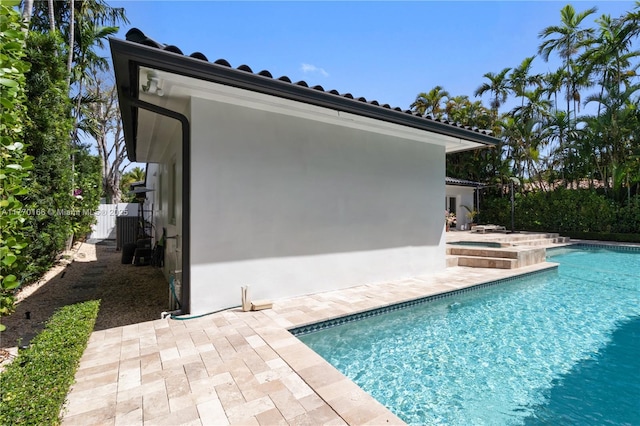 outdoor pool with a patio, an in ground hot tub, and fence