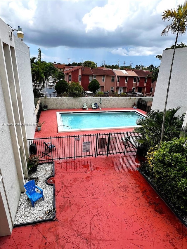 community pool featuring a residential view, fence, and a patio