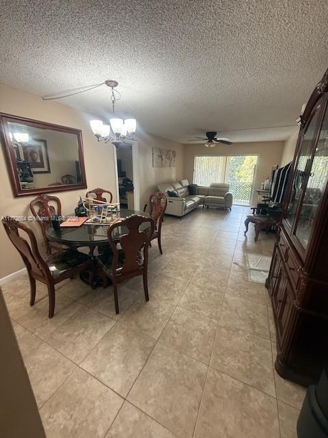 dining room with ceiling fan with notable chandelier and a textured ceiling