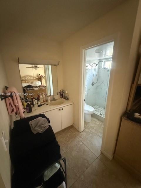 bathroom with toilet, vanity, a shower stall, tile patterned flooring, and ceiling fan