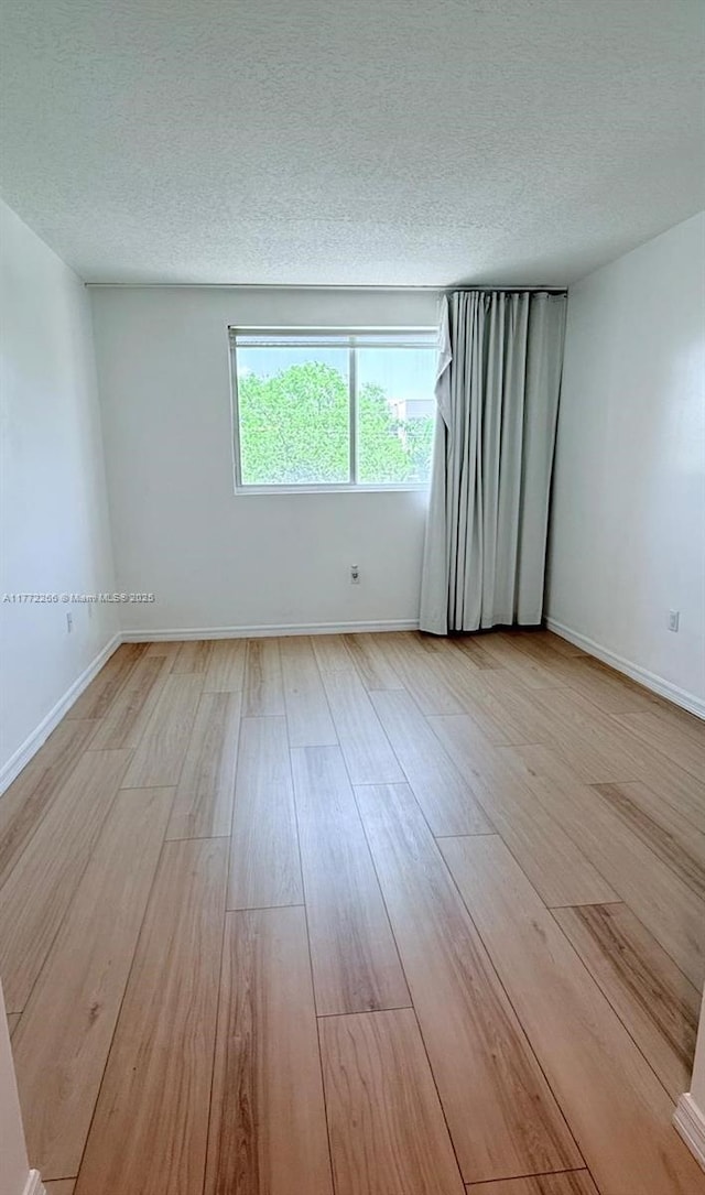 201 Golden Isles Dr Unit 311, Hallandale Beach, FL 33009 - empty room with light wood-style floors and a textured ceiling