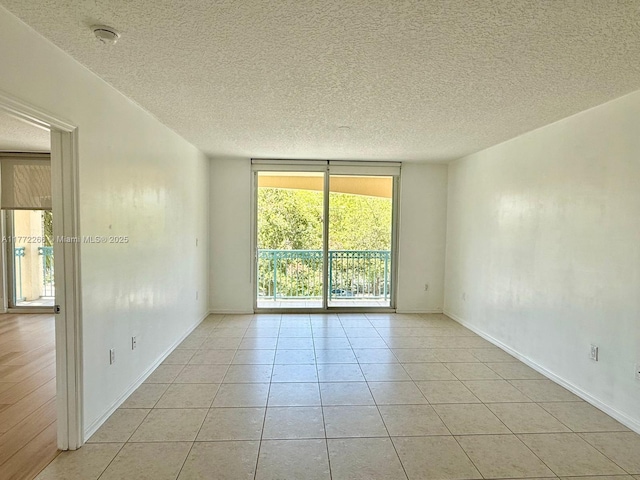 201 Golden Isles Dr Unit 311, Hallandale Beach, FL 33009 - unfurnished room with light tile patterned floors, a textured ceiling, a smoke detector, and floor to ceiling windows