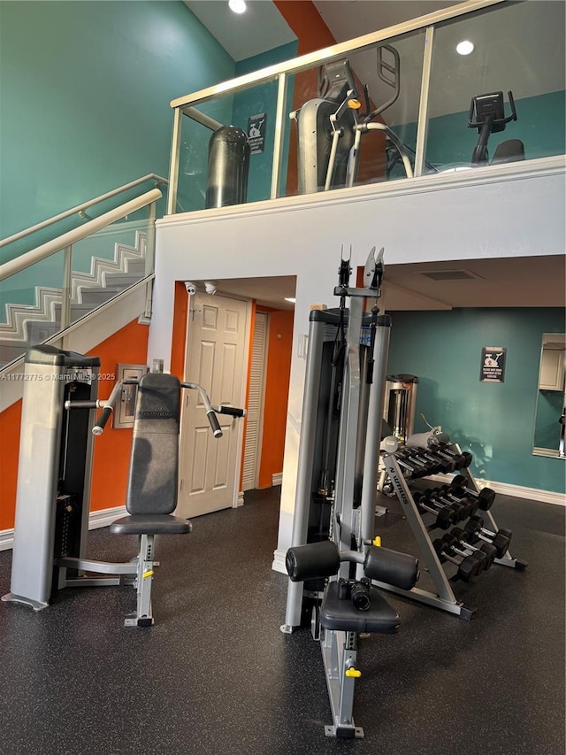 gym featuring a high ceiling and baseboards