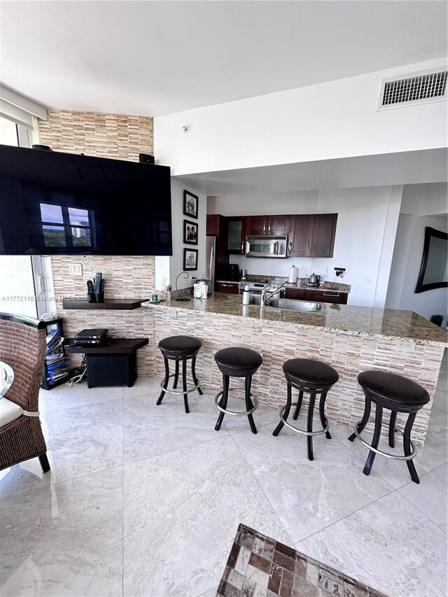 19900 E Country Club Dr Unit 1012, Aventura, FL 33180 - kitchen with dark brown cabinetry, a kitchen bar, visible vents, and appliances with stainless steel finishes