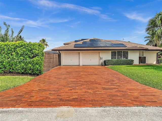 9461 SW 128th St, Miami, FL 33176 - view of front facade with stucco siding, decorative driveway, a front yard, solar panels, and a garage