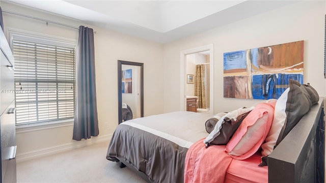 carpeted bedroom featuring ensuite bath and baseboards