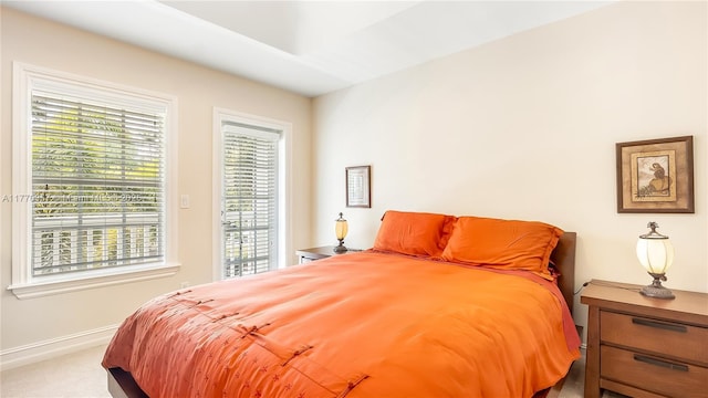carpeted bedroom featuring baseboards, access to outside, and multiple windows