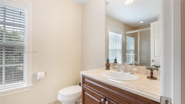 bathroom featuring a wealth of natural light, toilet, vanity, and a shower with door
