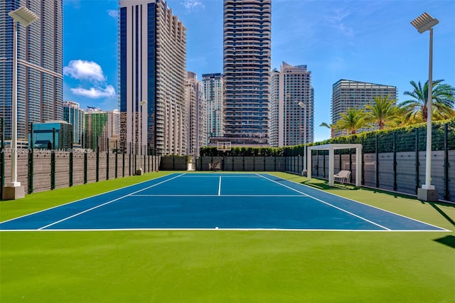 view of tennis court featuring fence and a city view