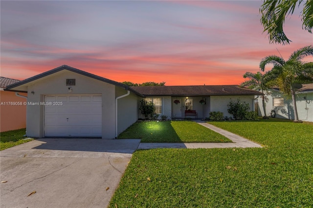 ranch-style home with a yard, stucco siding, a garage, and concrete driveway