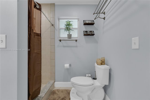 bathroom featuring toilet, a stall shower, baseboards, and tile patterned flooring