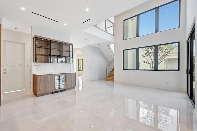 1419 N Lakeside Dr, Lake Worth, FL 33460 - unfurnished living room with light marble finish flooring, stairs, wine cooler, recessed lighting, and baseboards