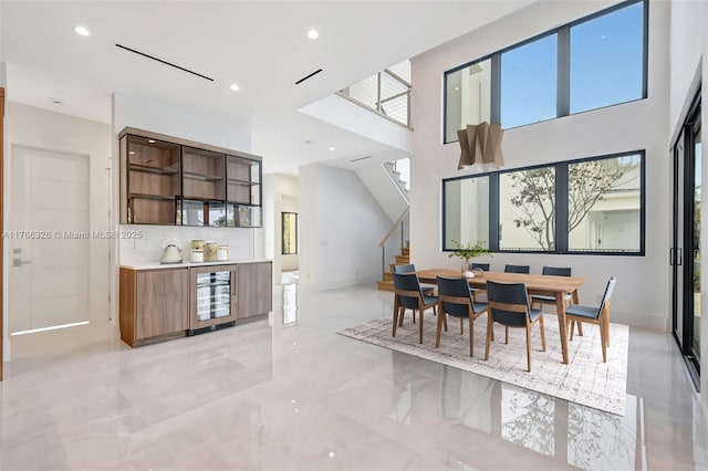 1419 N Lakeside Dr, Lake Worth, FL 33460 - dining space with stairs, beverage cooler, recessed lighting, light marble finish flooring, and a high ceiling