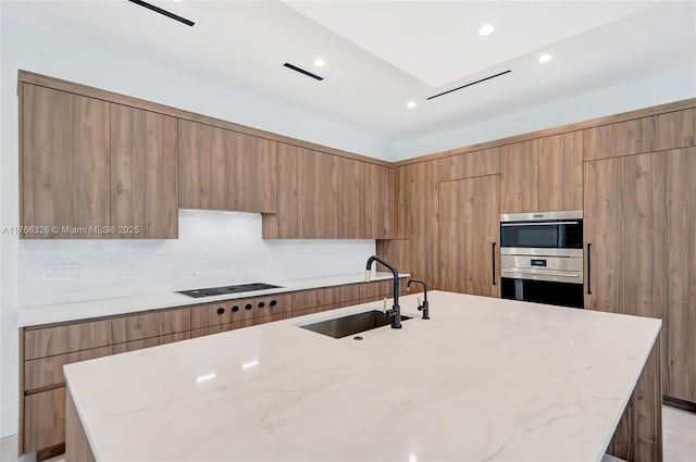 1419 N Lakeside Dr, Lake Worth, FL 33460 - kitchen with a sink, modern cabinets, black electric cooktop, a center island with sink, and light stone counters