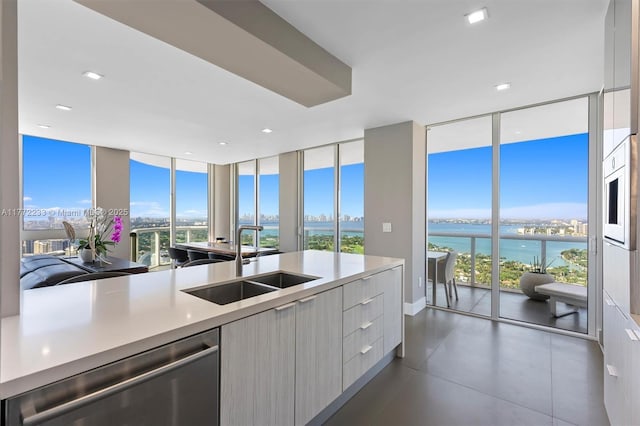 kitchen featuring stainless steel dishwasher, a sink, a wall of windows, modern cabinets, and light countertops